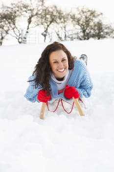 Young Woman Riding On Sledge In Snowy Landscape