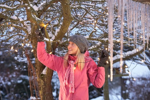 Teenage Girl Hanging Fairy Lights In Tree With Icicles In Foreground