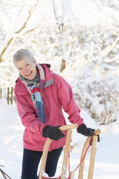 Senior Woman Holding Sledge In Snowy Landscape