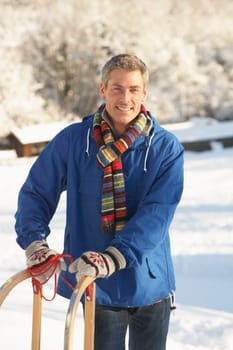 Middle Aged Man Standing In Snowy Landscape Holding Sledge