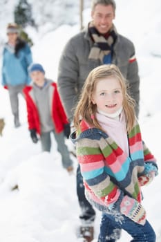 Family Enjoying Walk Through Snowy Landscape