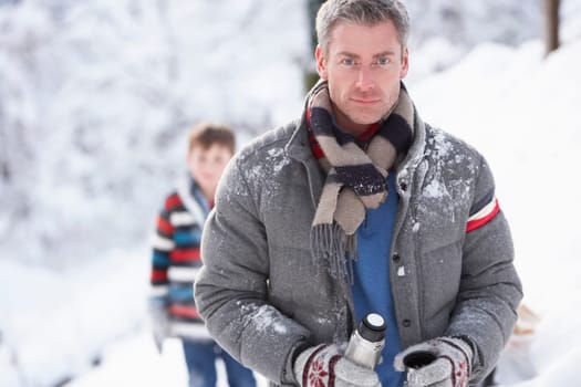 Family Stopping For Hot Drink And Snack On Walk Through Snowy Landscape