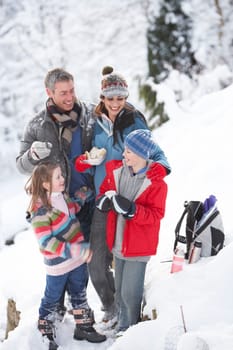 Family Stopping For Hot Drink And Snack On Walk Through Snowy Landscape