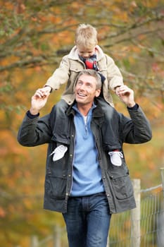 Man With Young Son On Shoulders Autumn Park