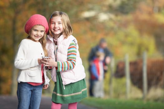 Two Young Girl Listening To MP3 Player Outdoors