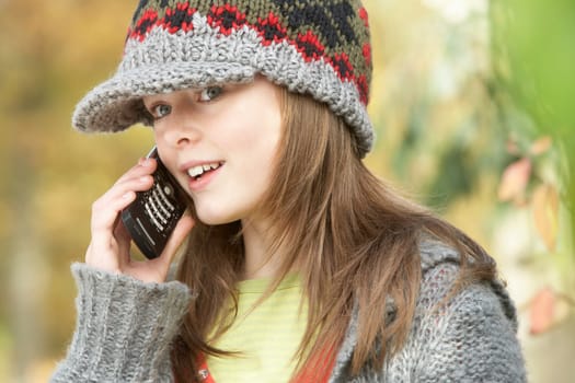 Head And Shoulders Of Young Girl In Autumn Woodland Using Mobile Phone