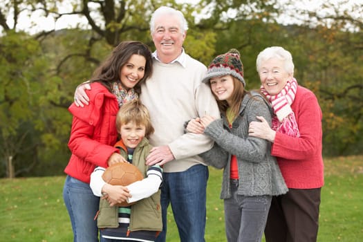 Grandparents With Grandchildren And Mother Holding Football Outside