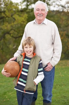 Grandfather With Grandson Holding Football Outside