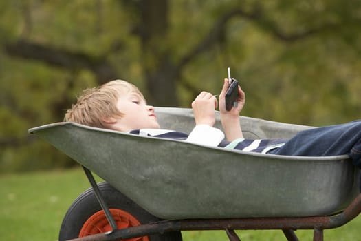 Young Boy Laying Wheelbarrow Using Smart Mobile Phone