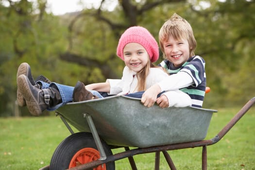 Boy And Girl Sitting In Wheelbarrow