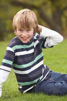 Young Boy Relaxing Outdoors Sitting On Grass