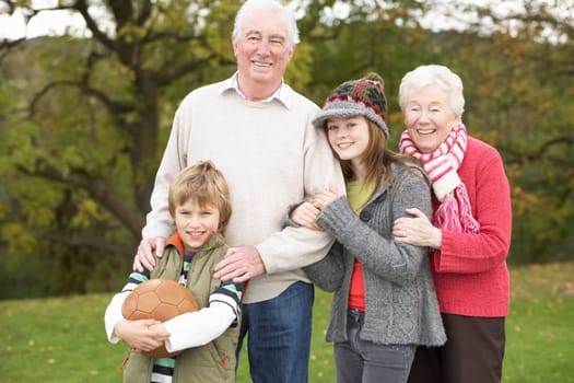 Grandparents With Grandchildren Holding Football Outside