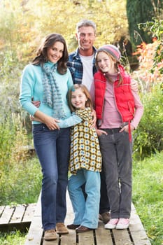 Family Group Standing Outdoors On Wooden Walkway In Autumn Landscape
