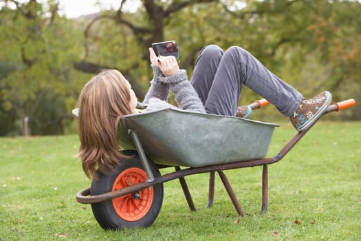 Young Girl Laying Wheelbarrow Using Smart Mobile Phone