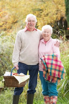 Senior Couple Outdoors With Picnic Basket By Autumn Woodland
