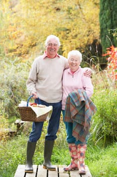 Senior Couple Outdoors With Picnic Basket By Autumn Woodland