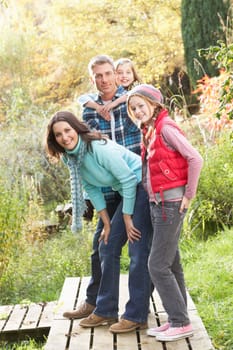 Family Group Standing Outdoors On Wooden Walkway In Autumn Landscape