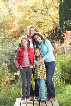 Family Group Standing Outdoors On Wooden Walkway In Autumn Landscape