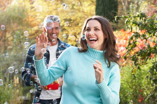 Couple Outdoors In Autumn Landscape With Bubble Machine