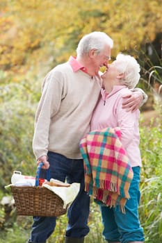 Romantic Senior Couple Outdoors With Picnic Basket By Autumn Woodland
