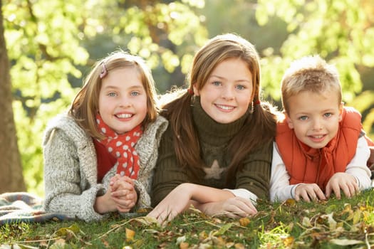 Group Of 3 Children Realxing Outdoors In Autumn Landscape