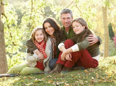 Family Group Relaxing Outdoors In Autumn Landscape
