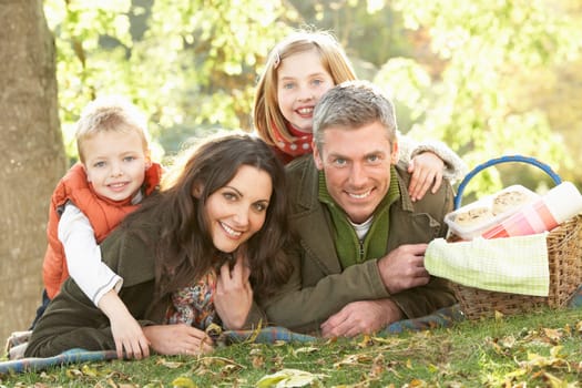 Family Group Relaxing Outdoors In Autumn Landscape