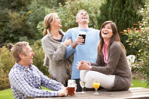 Group Of Friends Outdoors Enjoying Drink In Pub Garden