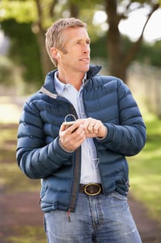 Man Listening To MP3 Whilst Walking In Autumn Park