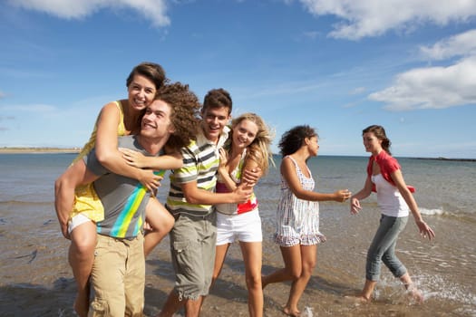 Group Of Young Friends Walking Along Summer Shoreline