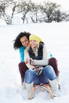 Couple Sledging Through Snowy Woodland