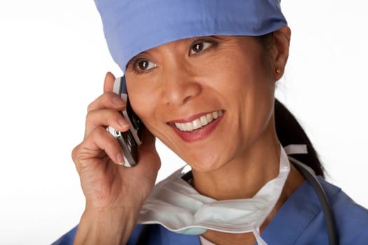 Closeup, cropped view of an Asian female medical professional wearing scrubs and talking on a cell phone. Horizontal shot. Isolated on white.