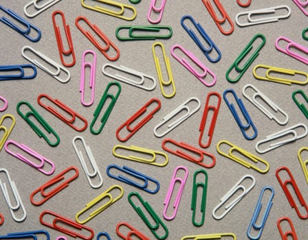 Multi colored paperclips on a gray table top. Horizontal shot.
