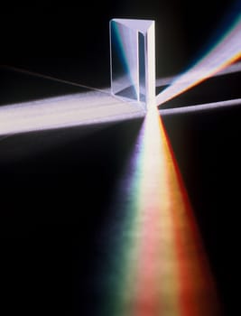 Light is being refracted though a prism which then splits the light into the various spectrum of colors. Vertical shot.
