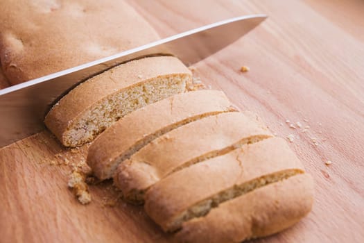 biscotti loaf being cut with a knife on a cutting board