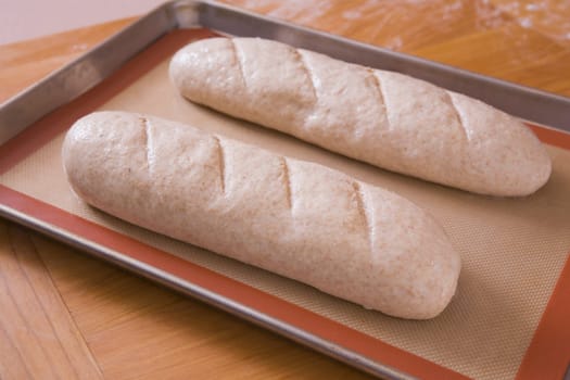 two uncooked loaves of bread on a baking sheet