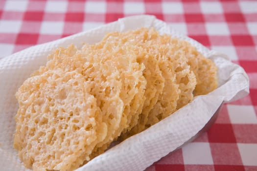 parmesan cheese laces in a basket on a red checkered table cloth