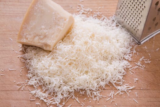 shredded parmeson cheese on a cutting board with a grater