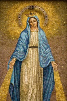 Mosaic of the Virgin Mary wearing a crown with device to give off light at night. Vertical shot.
