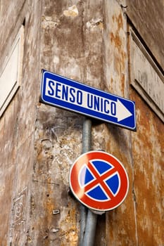 Close-up of Italian street signs, with one indicating 'one way' and the other of a red x through a blue circle. Vertical shot.