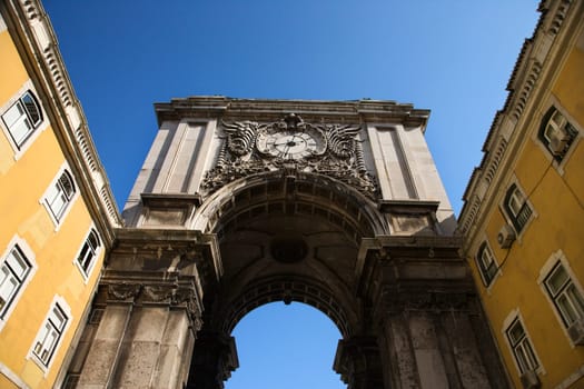 Arched tower with a clock spanning two buildings in Lisbon, Portugal. Horizontal shot.