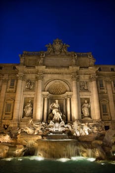 Trevi Fountain at night with lights under the water lighting the statuary. Vertical shot.