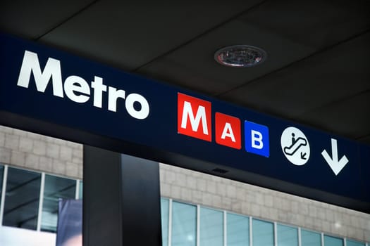 Metro sign indicating entrance via the escalator. Horizontal shot.