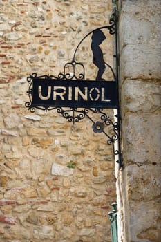 Graphic sign mounted on a wall exterior in Lisbon indicating a men's restroom. Vertical shot.