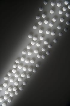 Overhead view of white round pills illuminated by a shaft of light. Vertical shot.