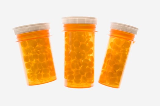 Three yellow plastic medicine bottles filled with pills. Horizontal shot. Isolated on white.