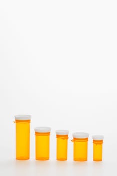 Yellow medicine bottles in diminishing sizes lined up in a row. Vertical shot. Isolated on white.