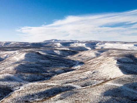 Aerial view of a snow-covered, hilly landscape. Horizontal shot.