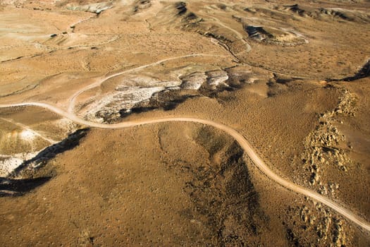 Aerial view of a of rural, desert landscape with a road running through it. Horizontal shot.