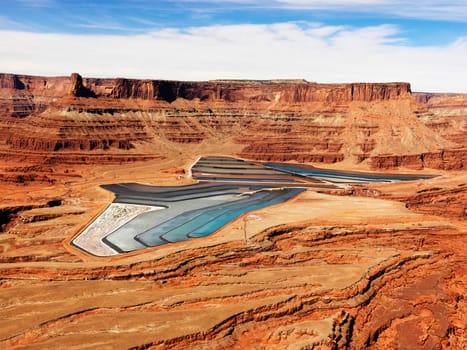 Aerial view of an arid, craggy landscape surrounding tailing ponds. Horizontal shot.